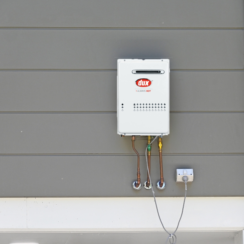 Dux Hot Water System continuous flow model installed on exterior wall with visible plumbing