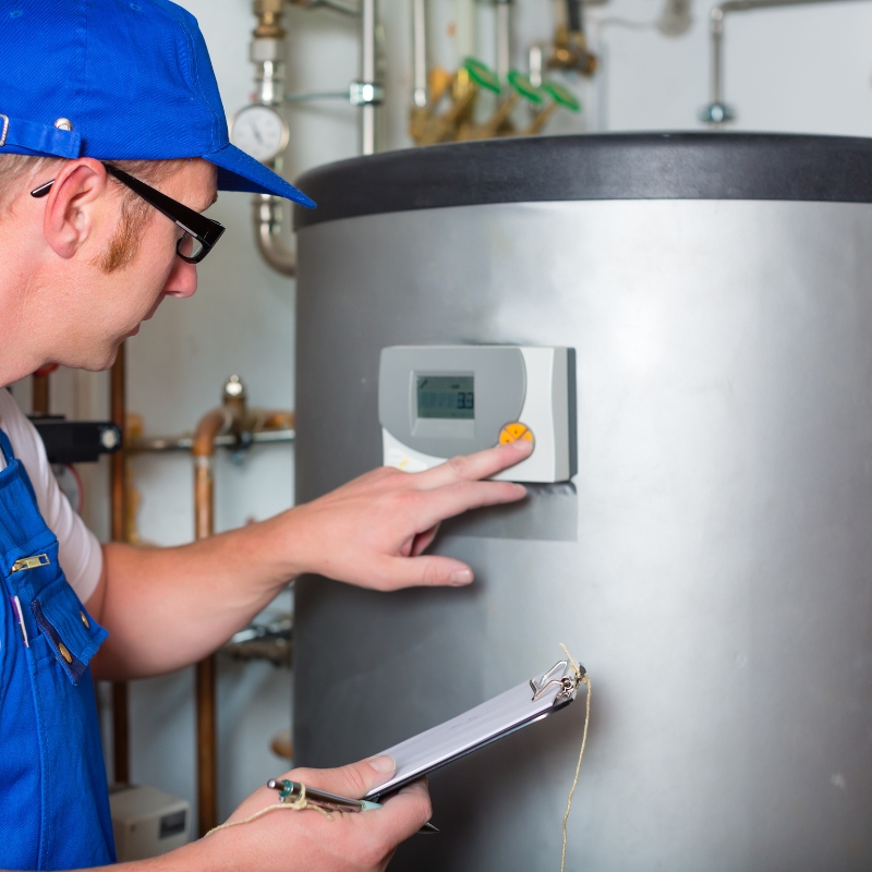 Technician adjusting control panel on a Rheem Hot Water System during service inspection.