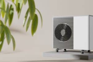 Modern Evo heat pump unit installed on a concrete slab, with a leafy green plant in the foreground. The image showcases the sleek design and compact size of Evo heat pumps, highlighting their suitability for residential settings.