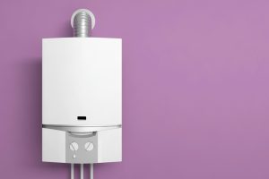 Modern white water heater mounted on a purple wall, illustrating considerations for when to replace a water heater.