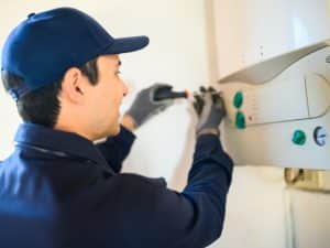 Technician installing a hot water system, emphasizing the importance to compare hot water systems for better choices.