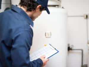 Technician inspecting a hot water system with a checklist, illustrating the need to compare hot water systems for maintenance.