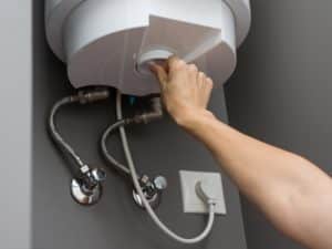 Person adjusting a hot water heater to prevent scale accumulation in the system.