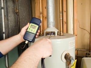 Technician testing a hot water heater for scale build-up with a digital meter.