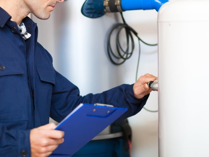 Plumber inspecting heater to prevent expensive hot water repair cost