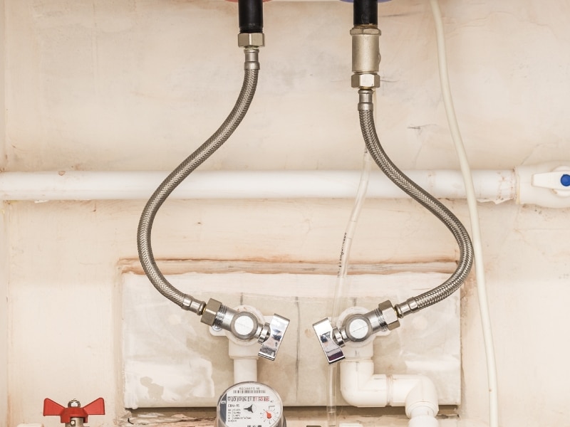 Hot water system issues with old valves and flexible pipe connections under sink.