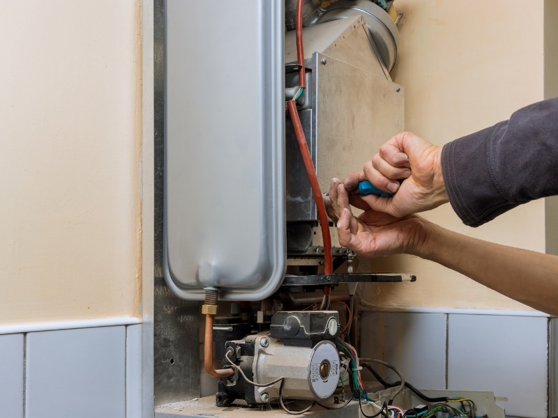 Technician installing gas hot water system inside home