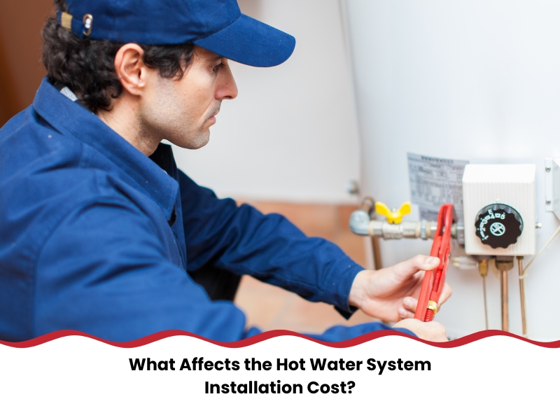 Plumber in blue uniform adjusting gas connection on a storage water heater, illustrating hot water installation cost.