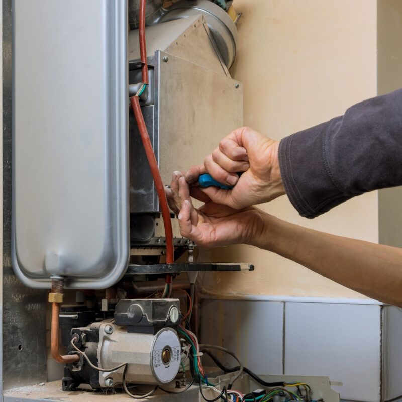 echnician using a screwdriver to repair a Rinnai hot water system.