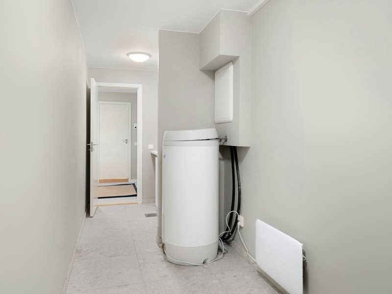 Newly installed hot water cylinder positioned in a clean utility room with modern plumbing connections.