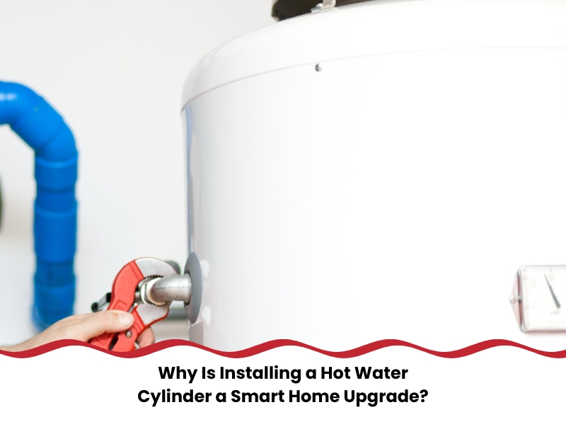 Plumber using a wrench to tighten fittings while installing a hot water cylinder in a modern home.