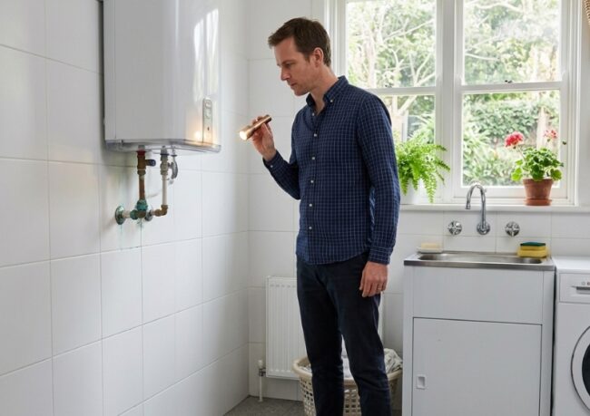 Sydney homeowner inspecting an ageing water heater for corrosion and leak warning signs.