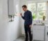Sydney homeowner inspecting an ageing water heater for corrosion and leak warning signs.