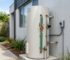 Electric hot water unit installed outdoors beside a Sydney home with insulated pipework, pressure control valves, and corrosion-resistant fittings.